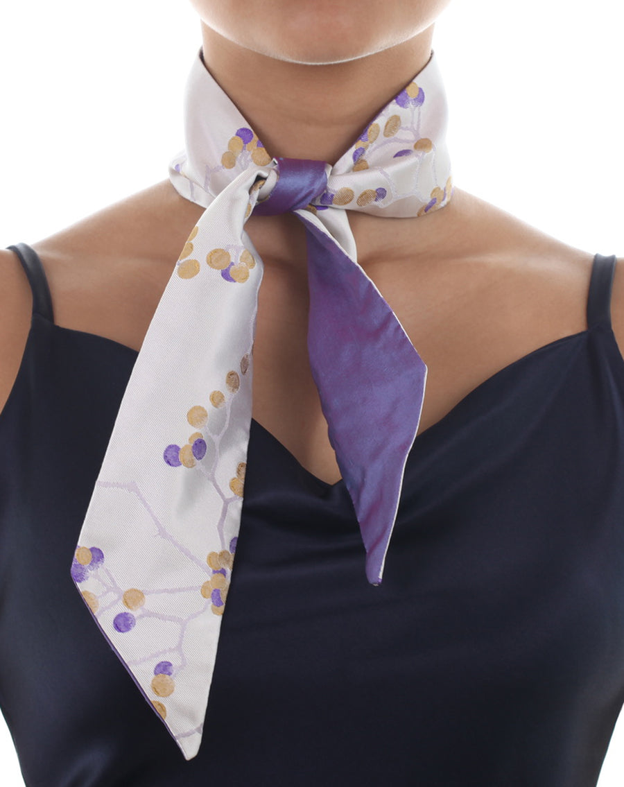 Female model in white & purple silk Mimi Fong skinny scarf with berries pattern, tied elegantly around neck on a white background