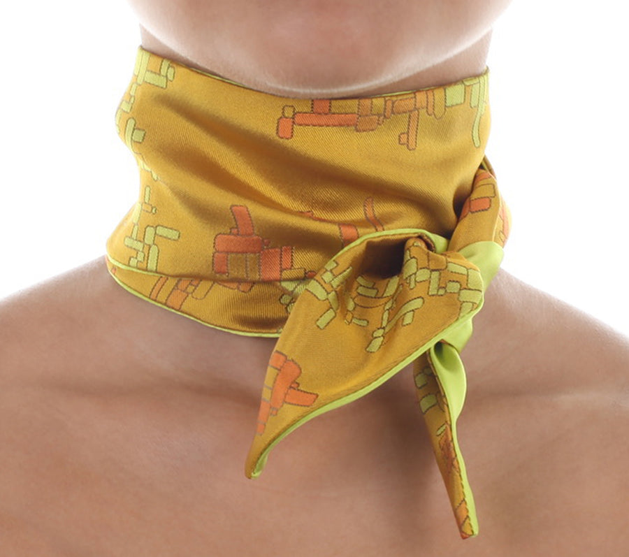 Female model in yellow silk Mimi Fong skinny scarf with geometric cubes pattern, tied elegantly around neck on a white background