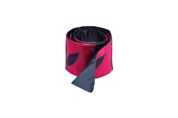 Rolled magenta silk Mimi Fong skinny scarf with blue leaves pattern on white background