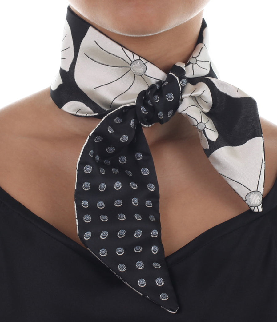 Female model in black & white silk Mimi Fong skinny scarf with lily pad pattern, tied elegantly around neck on a white background