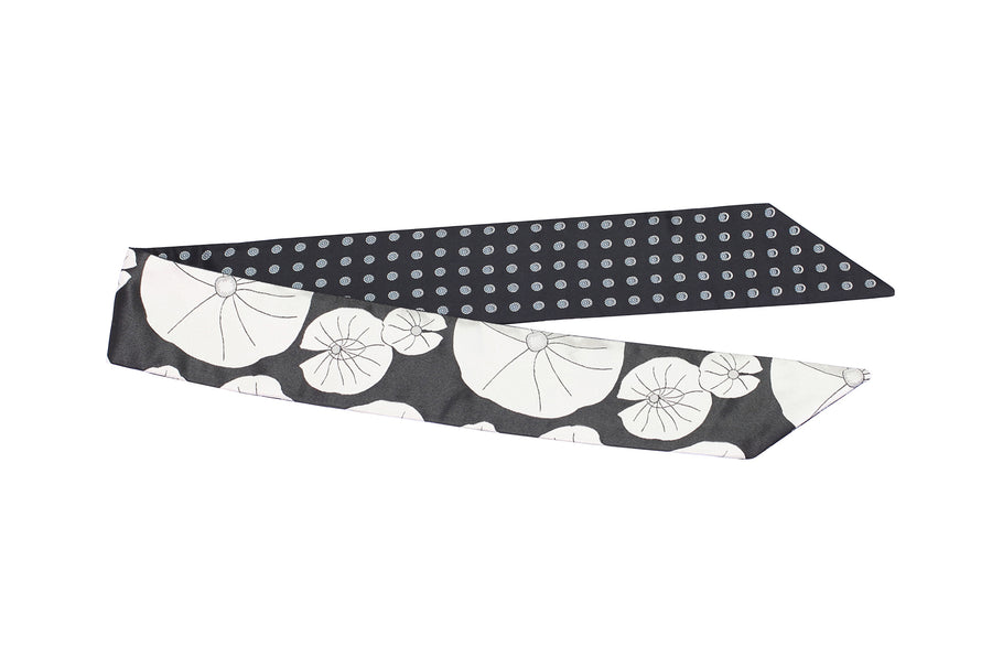 Folded flat black & white silk Mimi Fong skinny scarf with lily pad pattern on white background