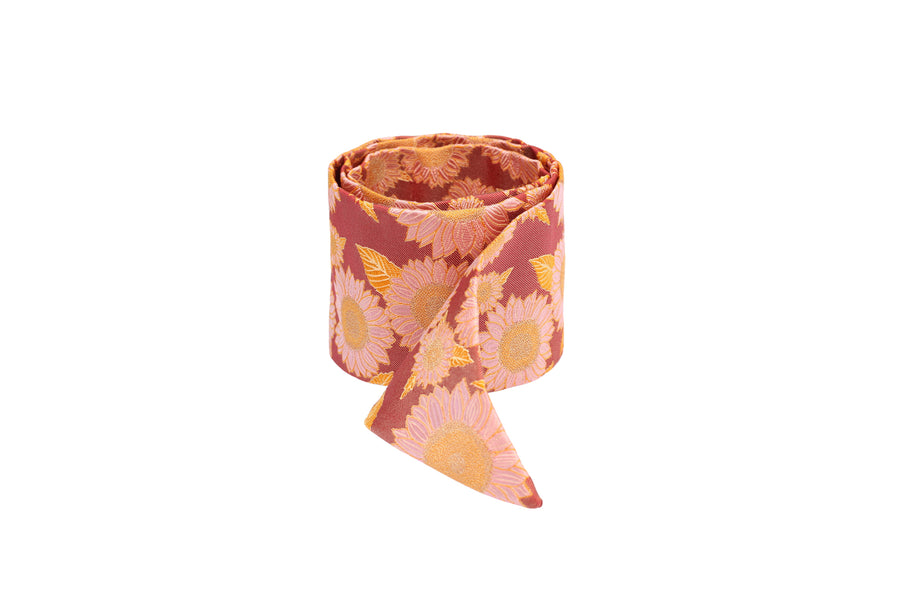 Rolled red silk Mimi Fong skinny scarf with pink & yellow sunflower pattern on white background