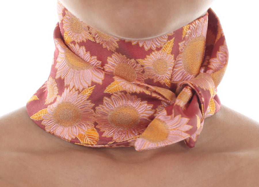 Female model in red silk Mimi Fong skinny scarf with pink & yellow sunflower pattern, tied elegantly around neck on a white background