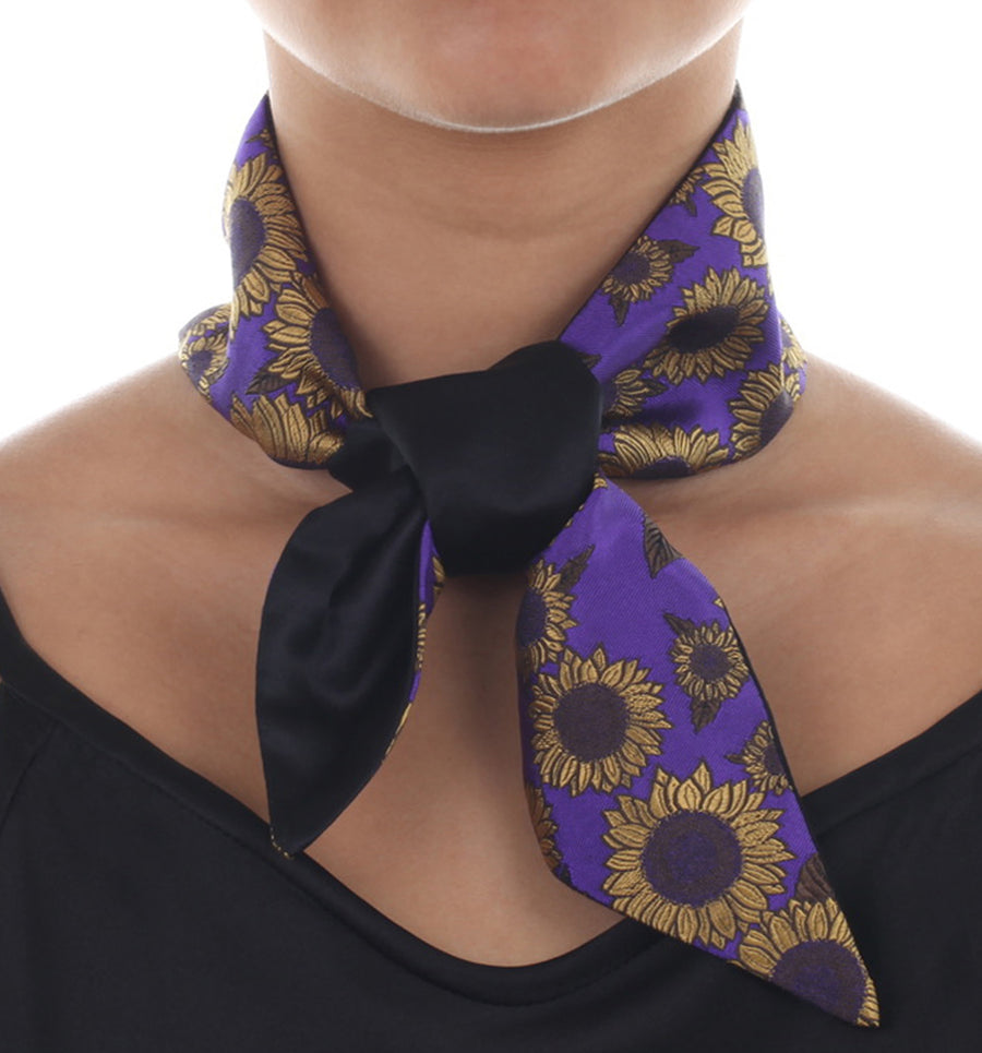 Female model in purple & black silk Mimi Fong skinny scarf with gold sunflower pattern, tied elegantly around neck on a white background
